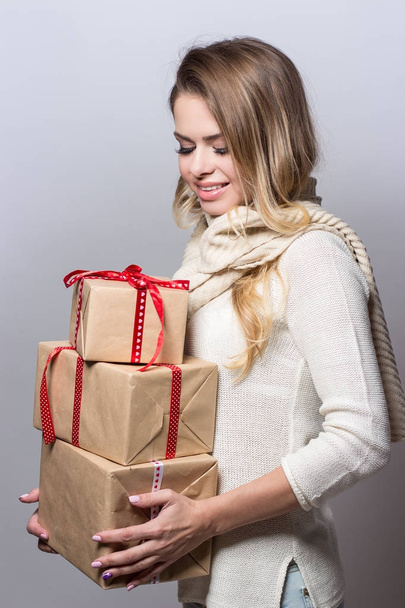 Νεαρή όμορφη γυναίκα εκμετάλλευση δώρα. Ευτυχισμένος κορίτσι κρατώντας δώρα σε άσπρο φόντο. Το νέο έτος. Χριστούγεννα. Γενέθλια. - Φωτογραφία, εικόνα