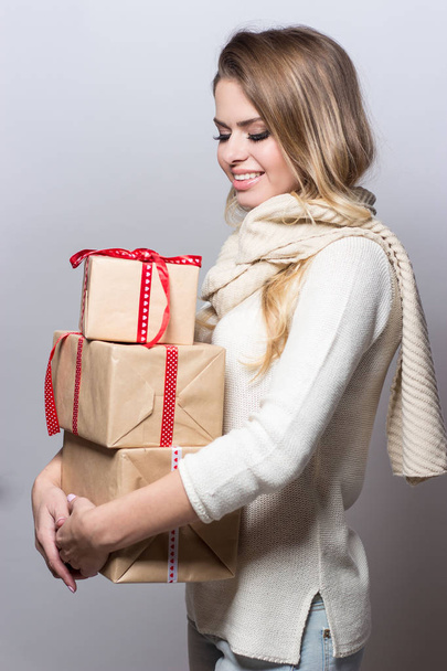 Joven mujer hermosa sosteniendo regalos. Chica feliz sosteniendo regalos sobre fondo blanco. Año Nuevo. Navidad. Cumpleaños.
. - Foto, imagen