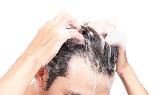 Closeup young man washing hair with white background, health care concept - Foto, afbeelding