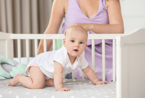 Cute baby in crib and mother at home - Valokuva, kuva