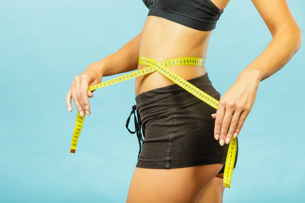 Fitness girl measuring her waistline - Foto, Bild