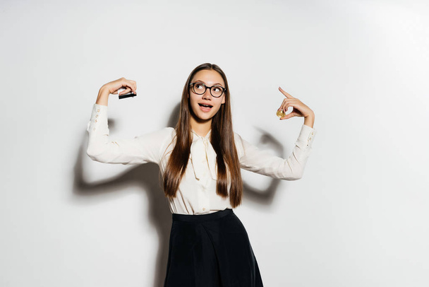 beautiful modern girl with glasses holds a gold bitcoin and a bank card in her hands, looks happy - Valokuva, kuva