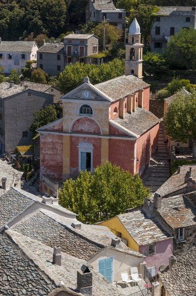 Κορσική: το ροζ ζωγραφισμένα εκκλησία του Saint Julie (Xvi αιώνα) στον ορίζοντα Nonza, χωριό για την δυτική ακτή της Cap Corse με παλιά σπίτια χτισμένο πάνω στους βράχους στην κορυφή 100 μέτρα στη θάλασσα  - Φωτογραφία, εικόνα