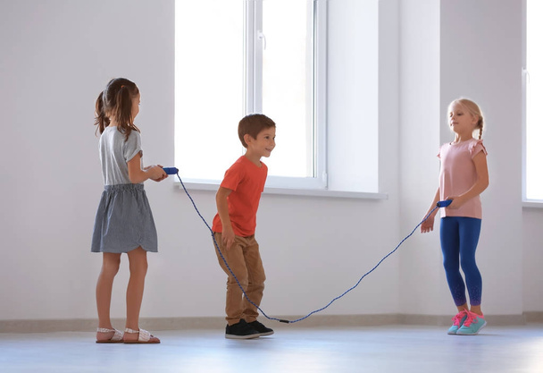 Adorable children skipping rope indoors - Foto, afbeelding