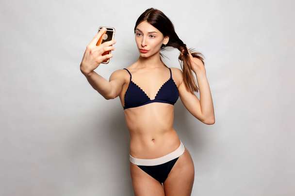pretty girl make a duck face, and take a self portrait with her smart phone - Фото, изображение