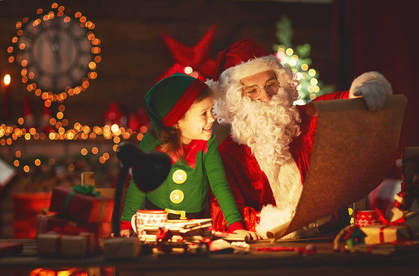Mikołaj czyta listę dzieci dobre do mały elf przez Christm - Zdjęcie, obraz