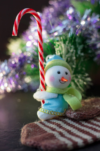 Іграшка сніговик тримає різдвяну цукеркову тростину в руках
. - Фото, зображення