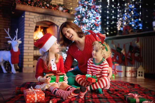 Familie mit Kindern am Weihnachtsbaum und Kamin.  - Foto, Bild