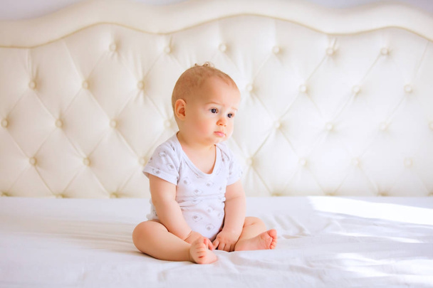 sad baby in white sunny bedroom - Φωτογραφία, εικόνα
