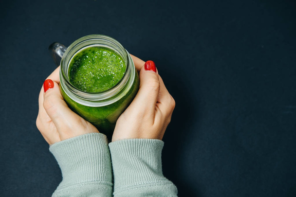 Female hands with green smoothies on a black table - Foto, Imagem