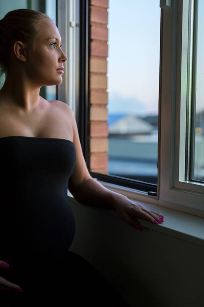 Kinézett az ablakon, átgondolt terhes nő - Fotó, kép