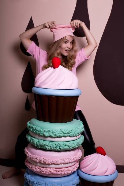 Χαρούμενη ξανθό μοντέλο σε ροζ t shirt και διασκεδάζοντας με μεγάλο καπάκι  - Φωτογραφία, εικόνα