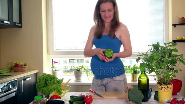 Těhotenství a výživy. Těhotná žena snížit paprika zeleniny na kuchyňském stole - Záběry, video