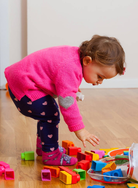 Toddler baby girl plays with soft rubber building blocks. - Photo, Image