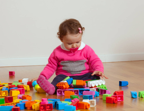 Μικρό παιδί μωρό κορίτσι παίζει με καουτσούκ μπλοκ δόμησης. - Φωτογραφία, εικόνα