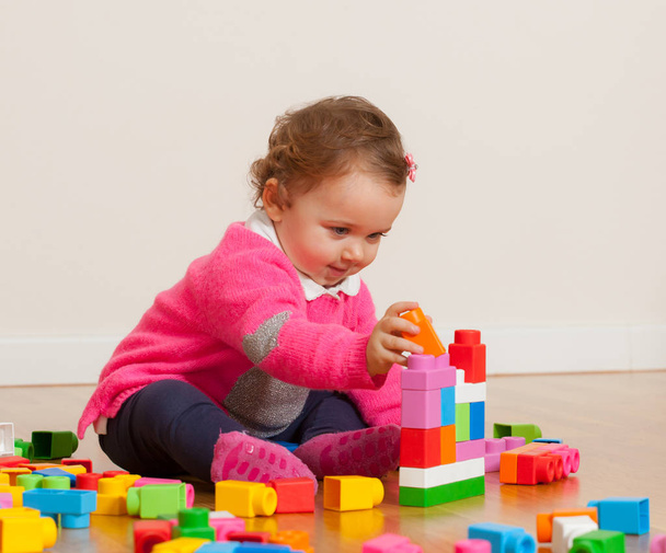 Tipegő baba lány játszik gumi építőelemek. - Fotó, kép