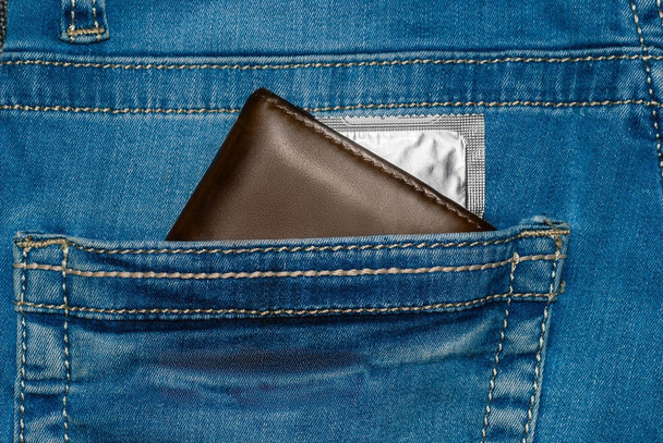 бумажник в кармане синих джинсов с серебряным презервативом
 - Фото, изображение