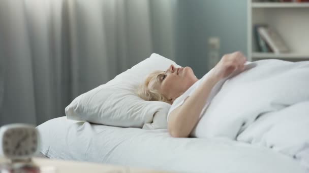 Healthy sleep. Blond senior woman sleeping in bed on orthopedic mattress - Imágenes, Vídeo