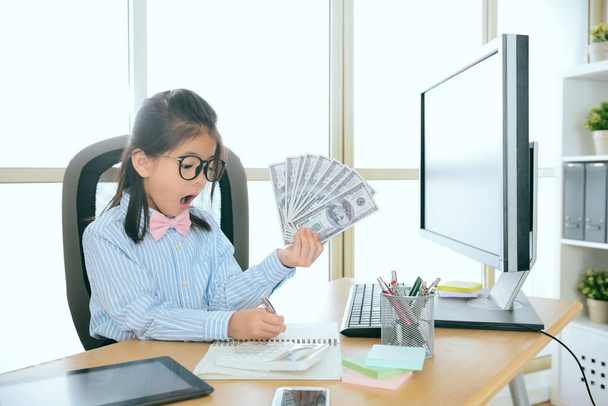 little girl office work holding many banknote - Foto, Imagen