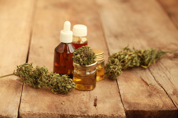 Foglie verdi di cannabis medicinale con olio di estratto su un tavolo di legno. medicina alternativa
 - Foto, immagini