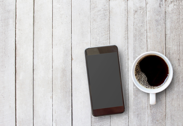  Smart phone and cup of coffee on old wooden background with cop - Foto, imagen