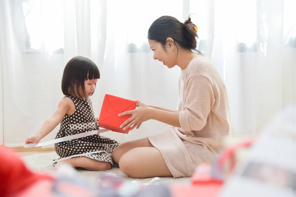 Asian Little girl and her Mother unwrapping a red gift box toget - Valokuva, kuva