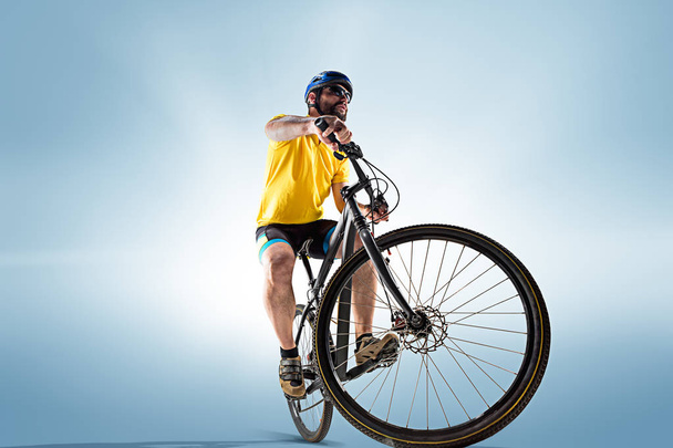 The bicyclist on gray, studio shot. - Zdjęcie, obraz