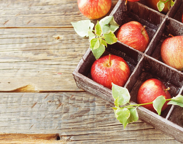 ώριμα κόκκινα μήλα σε ξύλινο κουτί σε ένα ρουστίκ τραπέζι, επιλεκτική εστίαση - Φωτογραφία, εικόνα
