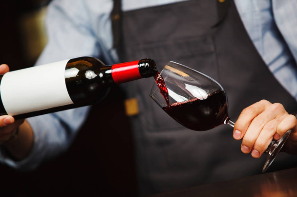 Man pouring wine into wineglass, male hand holding bottle - Foto, Bild
