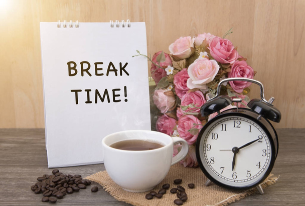 Xícara quente de café e despertador na mesa de madeira com flor de rosa
 - Foto, Imagem