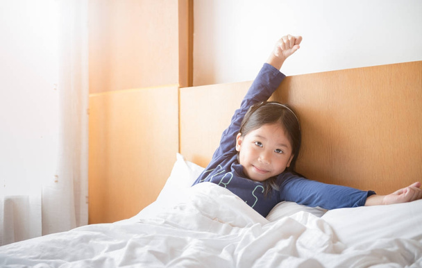 Asiatico carino ragazza si sveglia e stretching su letto
  - Foto, immagini
