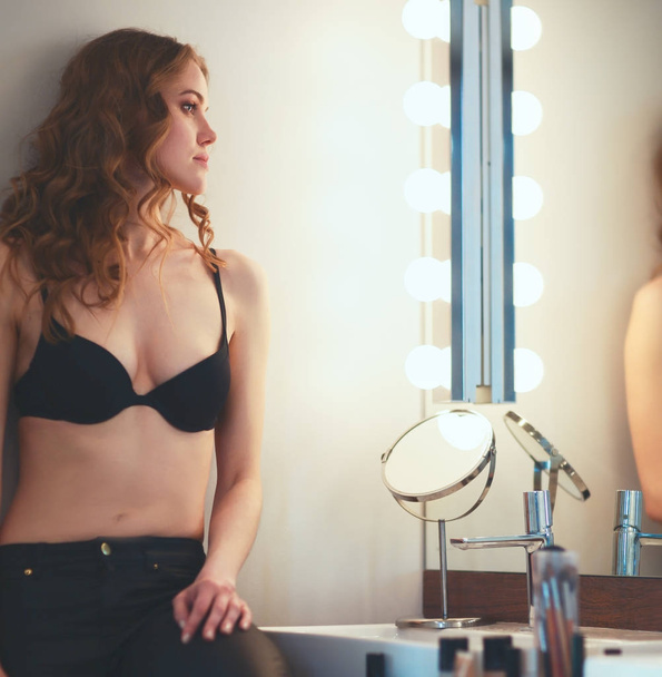Young woman looking herself in the mirror on bathroom - Foto, imagen