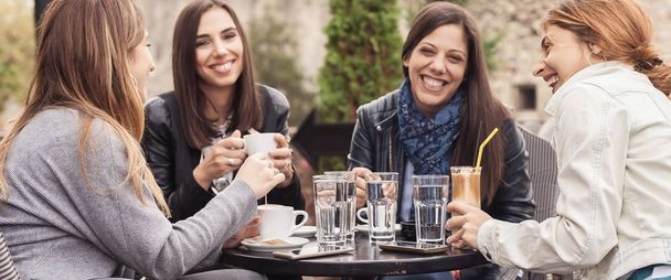 Four woman enjoying in cafe in beautiful sunny day - Photo, Image