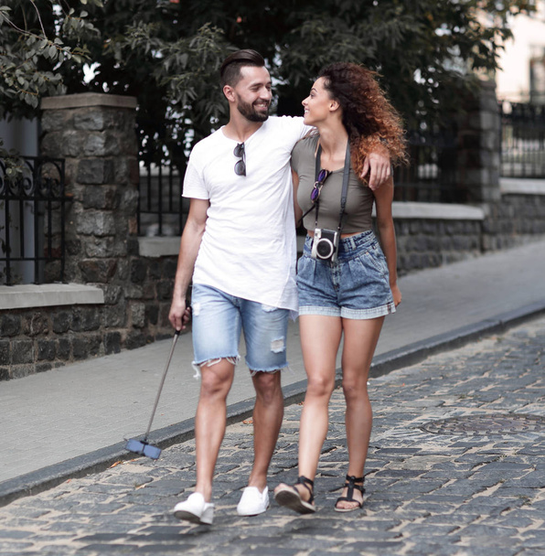 Cheerful young couple walking on urban street - 写真・画像