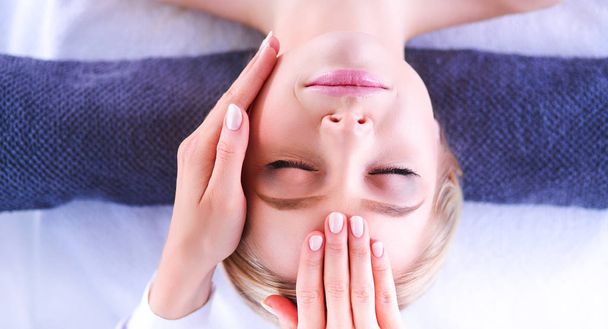 Young woman lying on a massage table,relaxing with eyes closed - 写真・画像