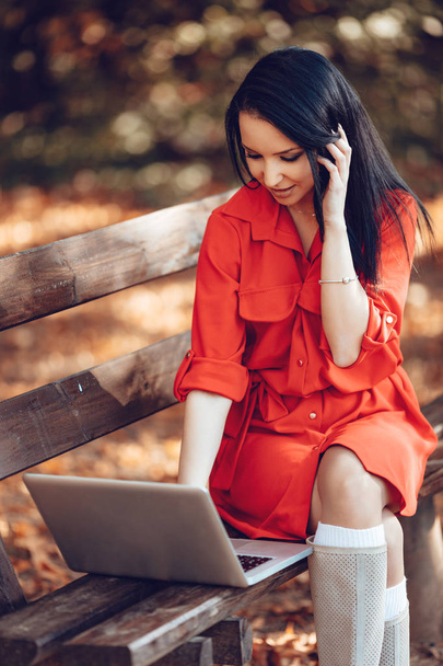 женщина сидит на скамейке и работает с ноутбуком
  - Фото, изображение