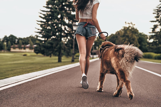 woman in jeans shorts running with dog - Foto, afbeelding