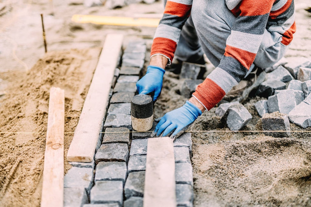 construction worker using industrial tools for stone pavement. granite blocks install details - Fotó, kép
