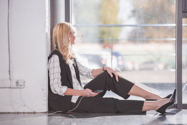 mujer de negocios sentada en el suelo y cargando teléfono
 - Foto, imagen