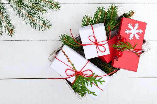 Новорічна, різдвяна тема. Зелені гілки, подарункові коробки на білому дерев'яному тлі. Святкове тло
. - Фото, зображення