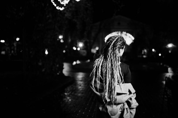 Girl with dreadlocks walking at night street of city against gar - Fotografie, Obrázek