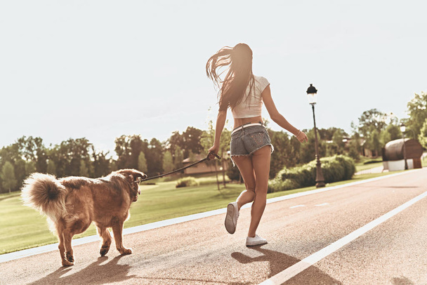 woman in jeans shorts running with dog - Photo, image