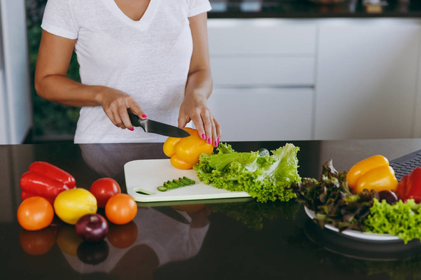 Nuori nainen leikkaa vihanneksia keittiöön veitsellä. Terveellinen ruoka - kasvissalaatti. Laihdutussuunnitelma. Terveellistä elämäntapaa. Kokkaan kotona. Valmista ruoka Sulje
 - Valokuva, kuva