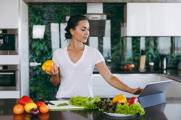 Fiatal nő látszó-on laptop konyha recept. Egészséges élelmiszer - zöldség saláta. Diéta fogalma. Egészséges életmód. Főzés otthon. Készítsünk élelmiszer. A hely a szöveg. - Fotó, kép