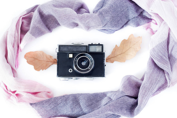 Autumn composition. Retro camera, autumn leaves and scarf on a white background. Nostalgia for autumn. The view from the top. . - Photo, Image