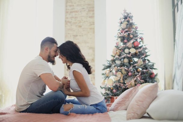 Happy couple of lovers sitting on the bed. Christmas interior. Lovers together - Foto, Imagen