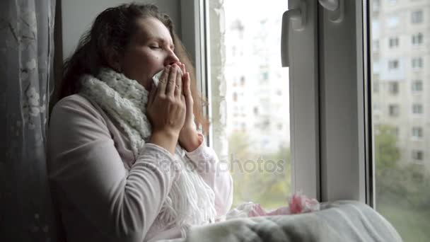 Uma mulher fria e gelada espirra. Menina soprando seu nariz enquanto sentado na janela
. - Filmagem, Vídeo