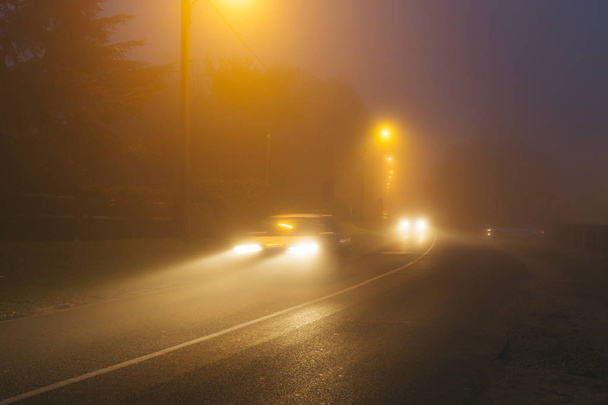 Estrada de asfalto rural na região da Normandia, França em dia nebuloso. Lâmpadas de rua e faróis de carro à noite. Tonificado
 - Foto, Imagem