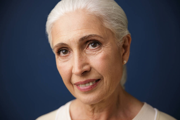 Close-up portrait of smiling mature caucasian woman, looking at  - 写真・画像