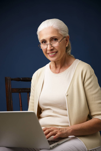 Cheerful old woman using laptop computer. Looking camera. - Photo, Image